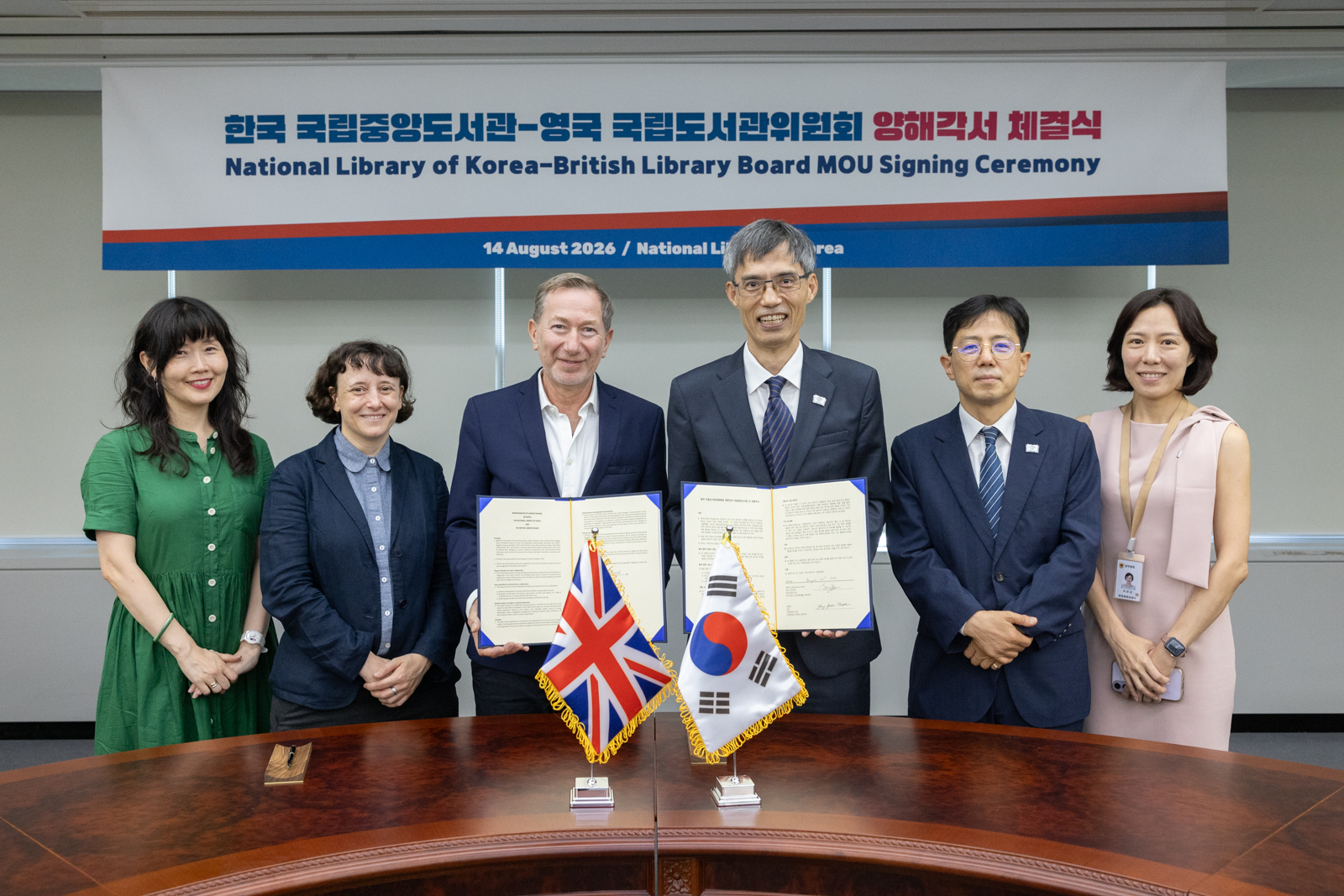 국립중앙도서관 남영준 관장과 영국 국립도서관위원회 영국 국립도서관장 직무대행 제레미 실버 (Jeremy Silver)가 양해각서에 서명을 하고 양측 관계자들과 기념촬영을 하고 있는 모습